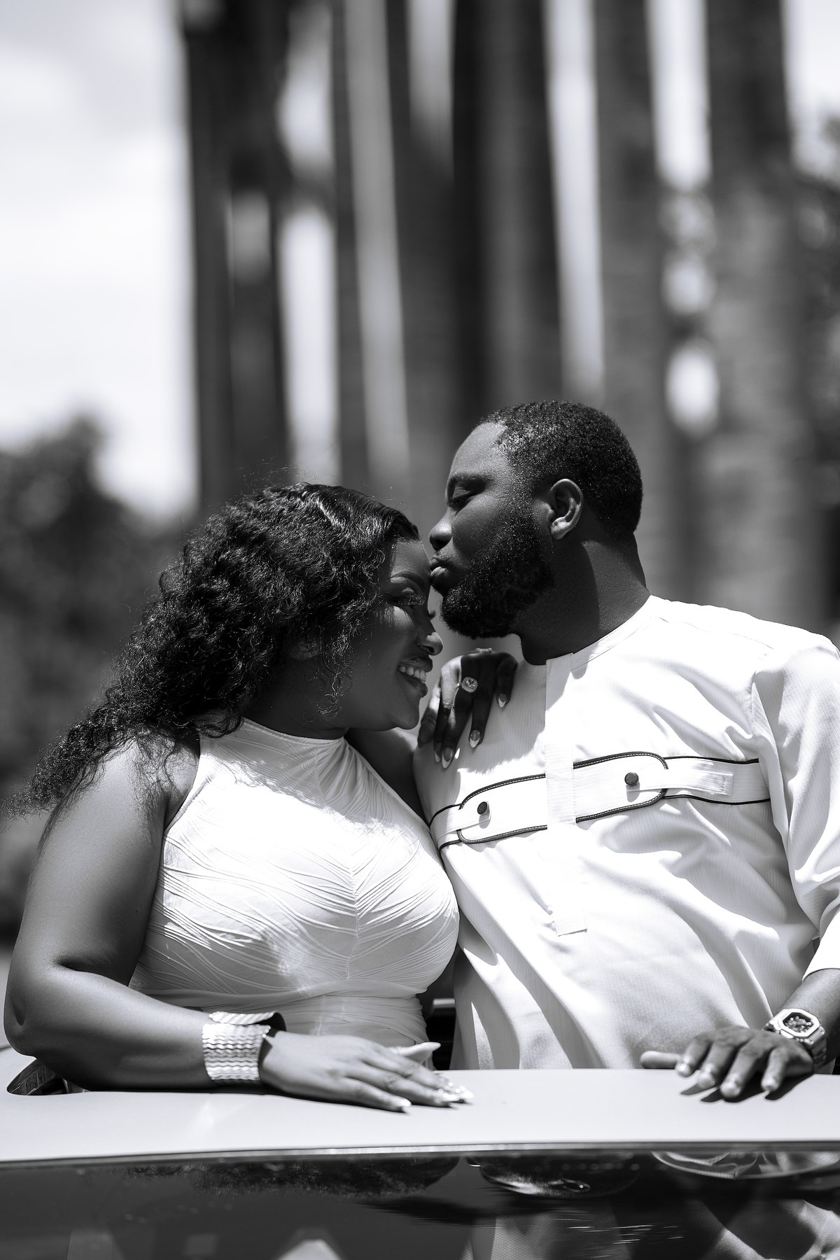 Samuel kissing Jennifer on the forehead in a black-and-white portrait